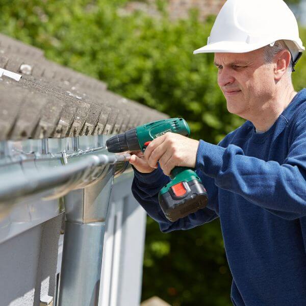 Gutter replacement in progress by Sydney Gutter Guys technician using power drill to install replacement gutters on a residential roof in Western Sydney Gutter replacement in progress by Sydney Gutter Guys technician using power drill to install replacement gutters on a residential roof in Western Sydney