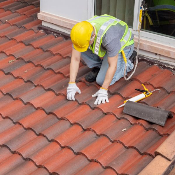 Roof restoration in progress with a roofer repairing and securing roof tiles on a residential property in Western Sydney by Sydney Gutter Guys