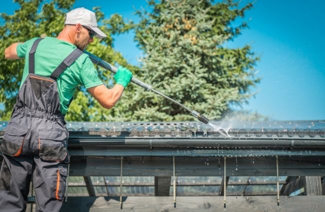 Worker pressure washing gutters as part of professional gutter cleaning by Sydney Gutter Guys Worker pressure washing gutters as part of professional gutter cleaning by Sydney Gutter Guys
